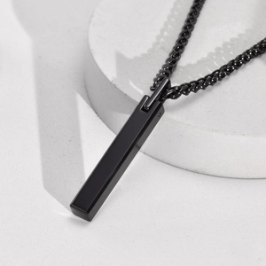 Minimalist black polished rectangle pendant with matching black metal chain on stone base