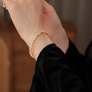 Detailed view of a gold tennis bracelet with cubic zirconia on a wrist for luxury fashion