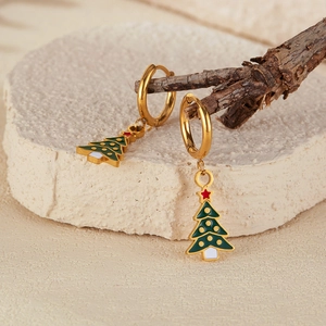 Detailed macro of green enamel Christmas tree earrings on a rustic wood and stone background