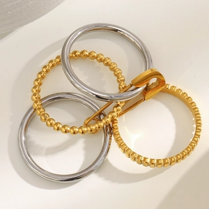 Macro view of stacked 18K gold and silver rings with pin detail on a textured base