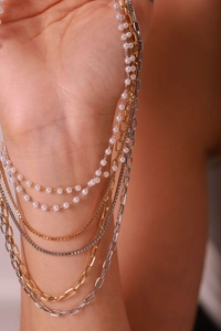 Close-up of triple-layered gold and silver chains with elegant white pearls on wrist