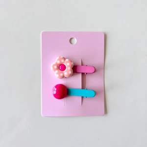 Detail of cute flower and bead hair clips on pink display card for young girls