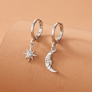 Asymmetric silver hoop earrings with star and moon charms featuring a central zircon
