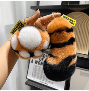 Detailed view of plush tiger stripe cat paw and tail keychains with lucky charm tags