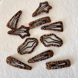 Detail showing various leopard print fabric hair clips in star and geometric shapes