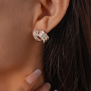 Close-up of silver multi-layer geometric loop earrings with textured metallic finish
