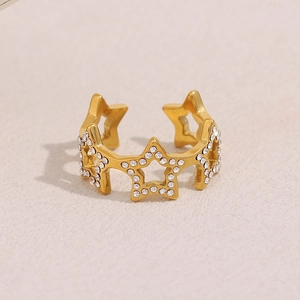 Detail of 18K gold plated star ring with white rhinestones on a warm white background