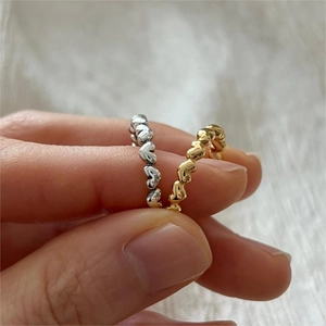 Detail view of gold and silver heart-shaped eternity rings with minimalist hollow design
