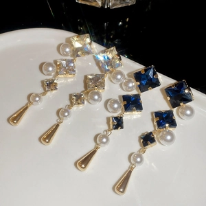Macro view of rhodium plated drop earrings with sparkling crystals and white pearls