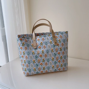 Détails du sac cabas en coton fleuri avec anses en cuir marron et rivets en laiton