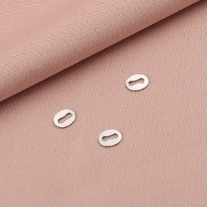 Three silver oval stainless steel eyelets for DIY jewelry on a pink fabric background