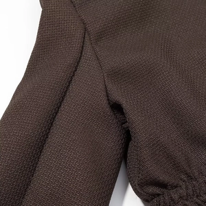 Macro detail of dark brown woven fabric texture and stitching quality of the casual jacket