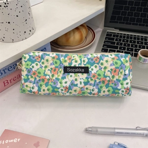 Detailed close-up of a floral canvas stationery pouch with a branded logo on a desk