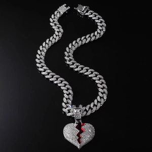 Iced out Cuban link necklace with broken heart pendant and red gems on black background