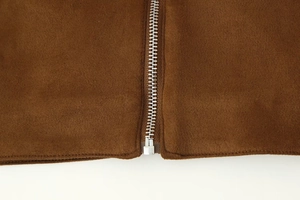 Detail of silver metal zipper on brown suede fabric of a fashion cropped jacket