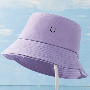 Détail du chapeau bob en coton lilas avec un motif de smiley noir brodé