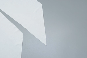Close-up detail of smooth white premium textile fabric pieces with elegant pleated texture