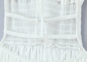 Detail of white cotton dress showing ruched fabric texture and delicate tie-up design