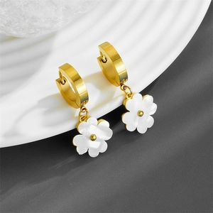 Detail of golden hoop earrings featuring white pearlescent flower charms on a tray