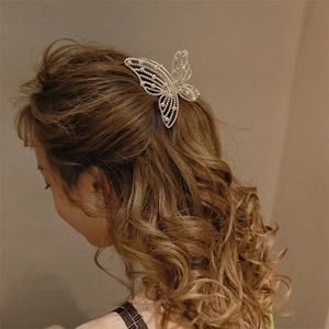 Close-up of a butterfly pearl hair claw clip on deep brown wavy hair from the back