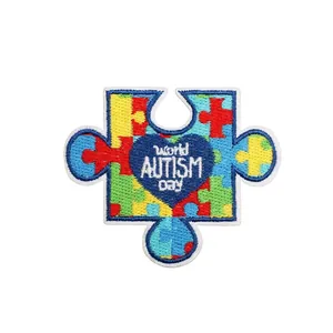 Detail of autism awareness puzzle patch with World Autism Day text and blue heart, 6.7x5.7cm