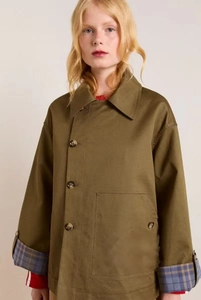 Detail of military green utility jacket featuring plaid cuffs and large patch pockets