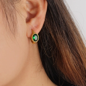 Detail of oval green gemstone earrings in gold-plated steel on model's ear