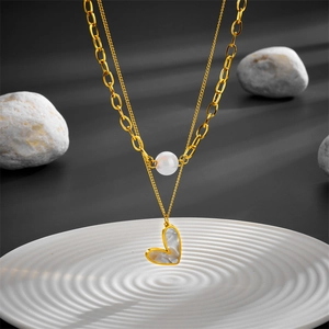 Close-up of a double-layer gold necklace featuring a heart pendant and a white pearl bead
