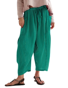Detail of green pleated wide-leg trousers with elastic drawstring waist and large side pockets