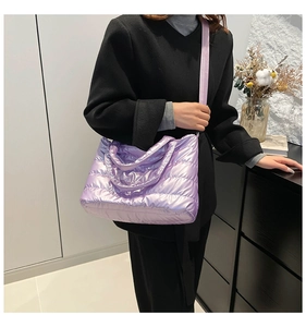 Detail of purple metallic quilted shoulder bag worn with a black coat for contrast