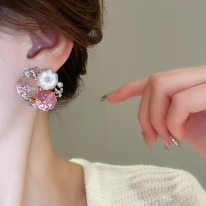 Close-up of elegant floral stud earrings with white and pink resin petals on a model