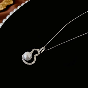 Macro shot of silver hollow gourd pendant featuring micro-pave zircons and a round white pearl