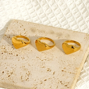 Trois bagues cœur en acier inoxydable plaqué or 18K sur un support en pierre beige