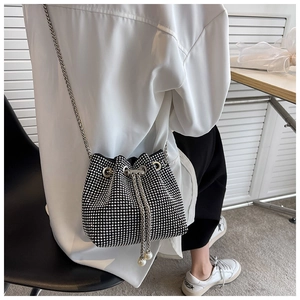 Detail of rhinestone bucket bag featuring silver chains and elegant pearl drawstrings