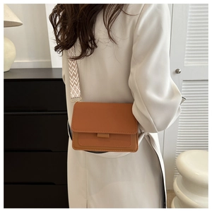 Dettaglio di una borsa a tracolla marrone vintage con ampia tracolla a motivi geometrici
