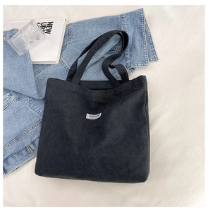 Detail of black corduroy tote bag with Fashion label on stylish lifestyle background