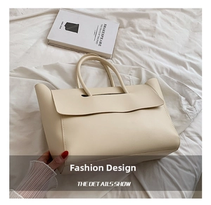 Detailed view of the large cream leather tote bag with curved flap and dual handles