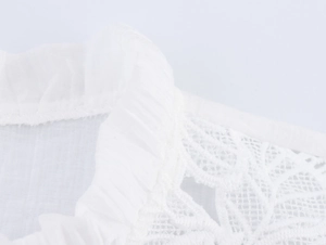 Close-up of white blouse with delicate lace patchwork and pleated fabric textures