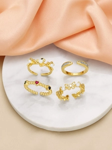 Detail view of four gold-plated rings with butterfly, pearl flower and heart-shaped gems