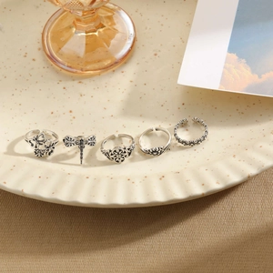 Close-up of vintage silver floral and insect rings with S925 hallmark on ceramic tray