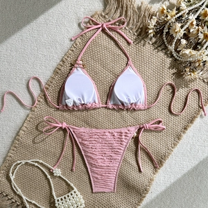 Detailed view of pink crinkle textured bikini with tie-side briefs on a rustic mat