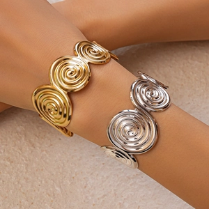 Detail of spiral textured open bangles in gold and silver finish on a model arm