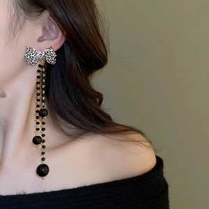 Close-up of leopard bow earrings with golden tassel chains and black beads