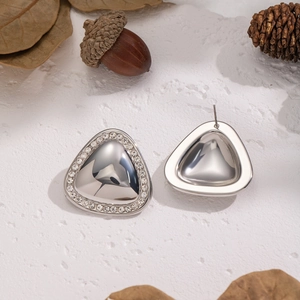 Dettaglio di orecchini a triangolo geometrico argento con strass su superficie materica