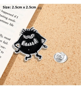Detailed size view of black monster enamel pin showing 2.5cm dimensions on cork background