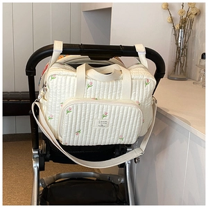 Détail du sac de poussette matelassé beige avec broderies tulipes et bandes velcro