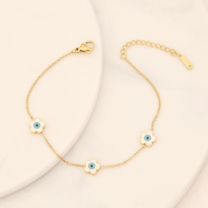 Close-up of golden flower charms with evil eye motifs on a delicate stainless steel bracelet