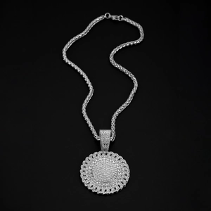Macro detail of silver plated hip hop pendant with iced out crystals and twist chain