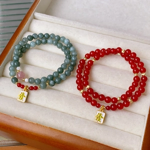 Detail of red agate and green bead double-layer bracelets with gold character charm
