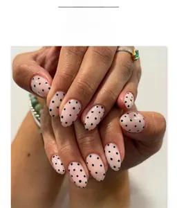 Faux ongles ovales courts avec base rose et motif à pois noirs pour femmes